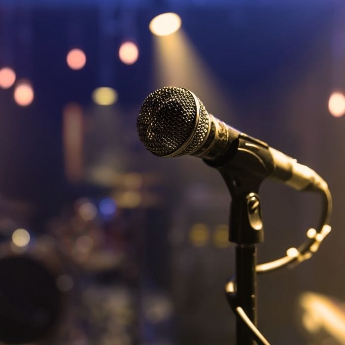 A closeup of a microphone with warm lights in the background, signalling the start of a show.