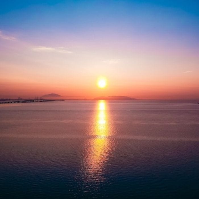 A romantic sunset, with warm and cold tones on the horizon, observing the penang bridge by the side.